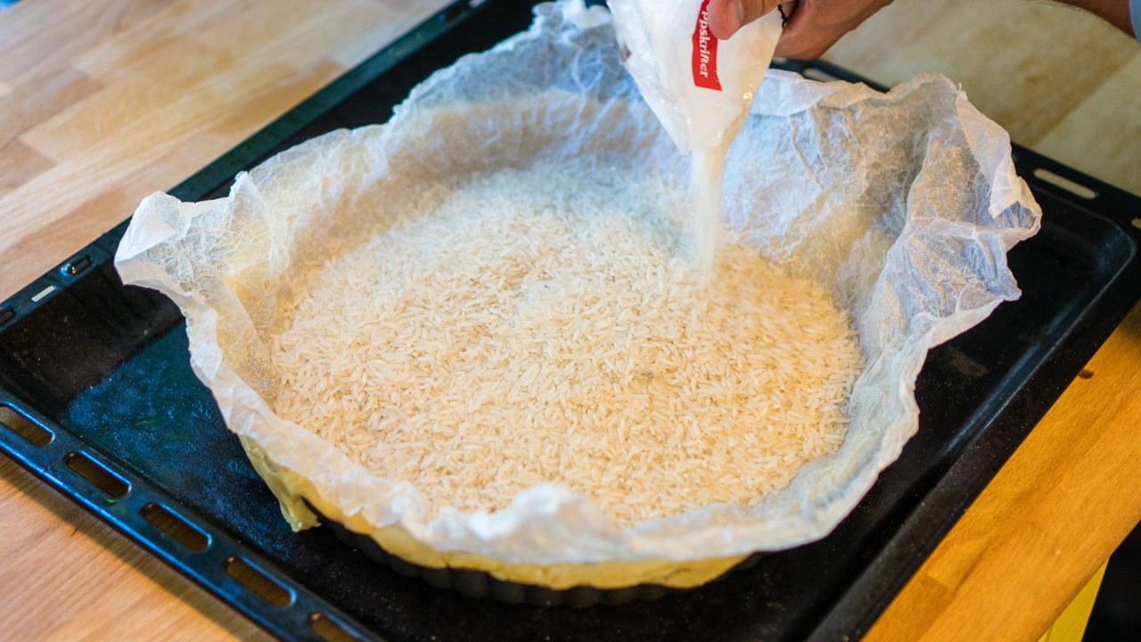 Formen dekkes med et bakeark, og fylles opp med ris for å gi tyngde.